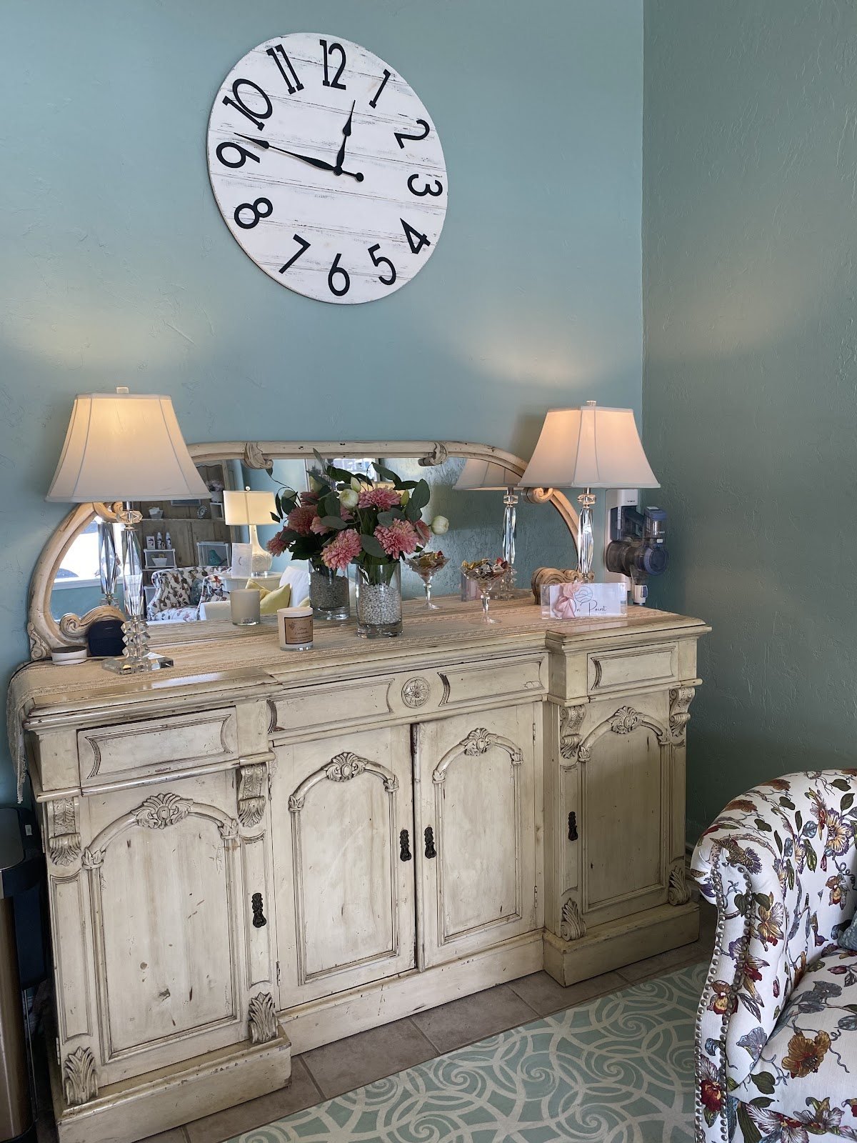 Cream console with lamps, fresh flowers and a large wall clock in the studio